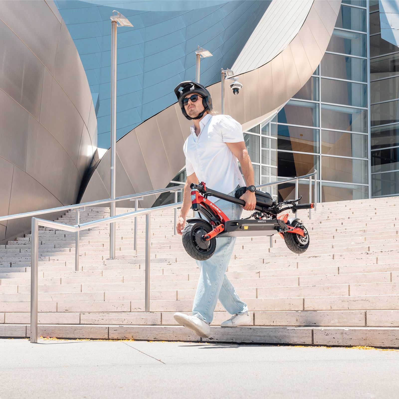 Person riding a red electric scooter in an urban setting with trees and buildings in the background.